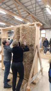 Menschen beim Einbau von Baustrohballen in Holzrahmen